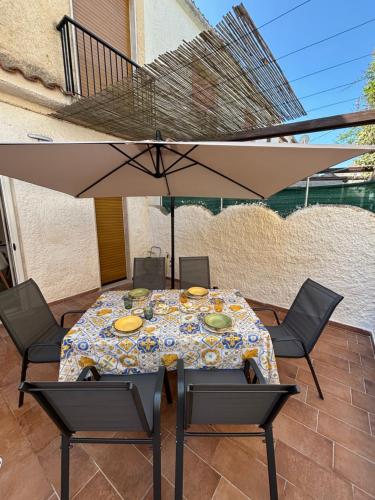 Una mesa con sillas y una sombrilla en un patio. en White Moon, en Fontane Bianche