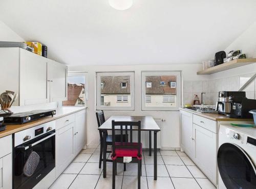 a kitchen with white cabinets and a table with chairs at A great place to stay, 3 rooms and a good location in Stuttgart