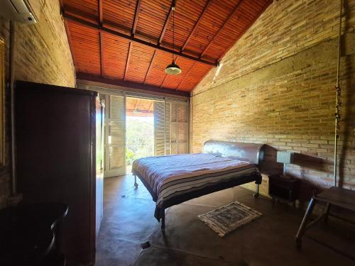 a bedroom with a bed and a brick wall at SHB - Chácara Koxixo, Piscina, Refúgio Urbano e Conforto in Presidente Prudente