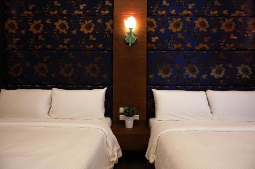 two beds with white sheets and a wall with flowers at Buckingham Palace B&B in Beipu