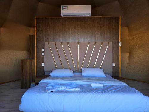 a bedroom with a large bed with a wooden headboard at WADI RUM GUlDE , CAMP & TOUR in Wadi Rum