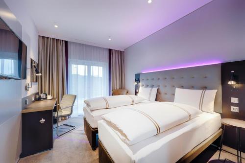 a hotel room with a large bed and a desk at Premier Inn Regensburg City Centre in Regensburg