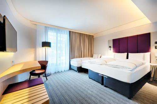 a hotel room with two beds and a desk at Premier Inn Heilbronn City Centre in Heilbronn