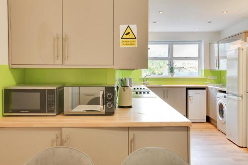 a kitchen with a microwave oven and a stove at City Centre GuestHouse By Luxiety Stays Cambridge Perfect For Families With Affordable Rates in Cambridge