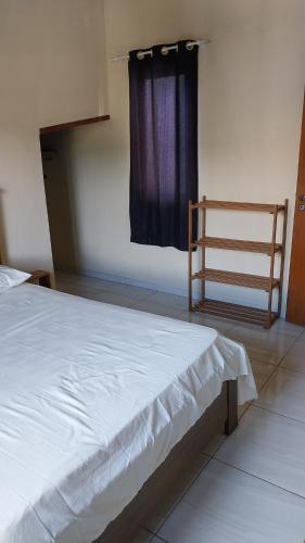 a bedroom with a white bed with a blue curtain at Sobrado entrada de Paraty in Paraty