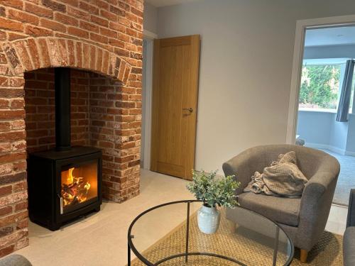 a living room with a brick fireplace and a chair at Marzion House with Hot Tub in Tattershall Thorpe