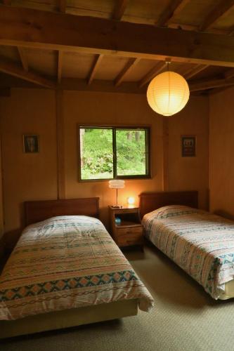 a bedroom with two beds and a window at Warm Spacious Forest Chalet & Private Onsen in Minakami