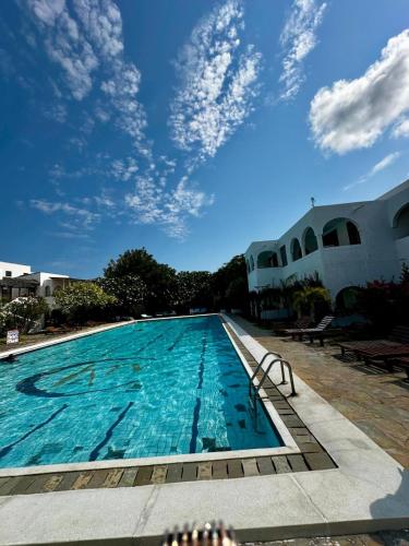 a swimming pool with a blue sky in the background at Jean pierre studio apartment in Malindi