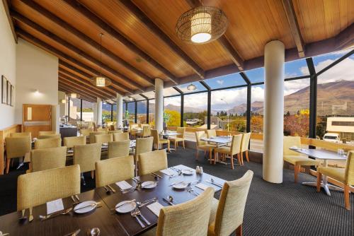 a dining room with tables and chairs and windows at Copthorne Hotel & Apartments Queenstown Lakeview in Queenstown