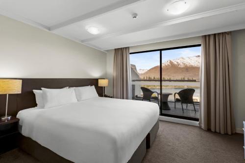 a hotel room with a bed and a large window at Copthorne Hotel & Apartments Queenstown Lakeview in Queenstown