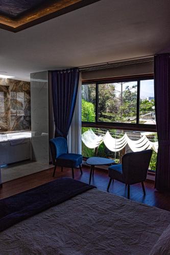 a bedroom with a bed and chairs and a large window at Hotel Terra in Arequipa