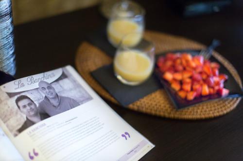 a book on a table with a plate of fruit and orange juice at La Banchina Holiday Rooms in Trani