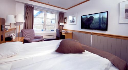 a hotel room with a bed and a tv on the wall at Home Hotel With in Tromsø