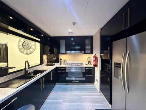 une cuisine avec des armoires noires et des appareils en acier inoxydable dans l'établissement เพ้นท์เฮ้าส์ Boulevard - Point Downtown Dubai, à Dubaï