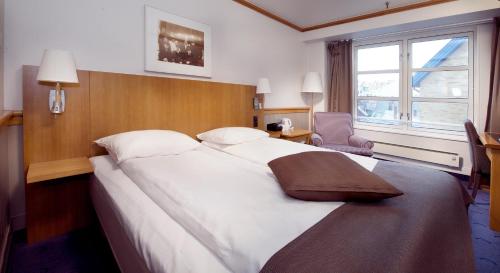 a large white bed in a hotel room with a window at Home Hotel With in Tromsø