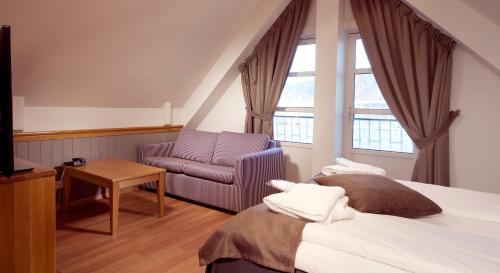 a hotel room with a bed and a chair at Home Hotel With in Tromsø