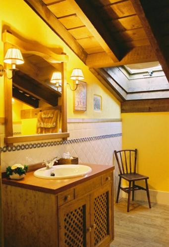 a bathroom with a sink and a mirror and a chair at El Encanto in Miraflores de la Sierra