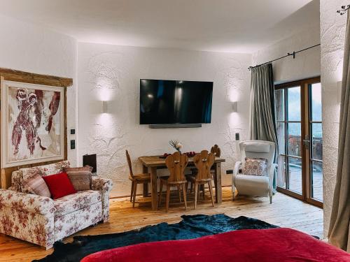 Una sala de estar con una mesa y un televisor en la pared. en Studio Wasserfall, en Flattach