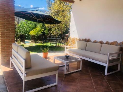 eine Terrasse mit Sofa, Tisch und Sonnenschirm in der Unterkunft Villa Lina in Órgiva