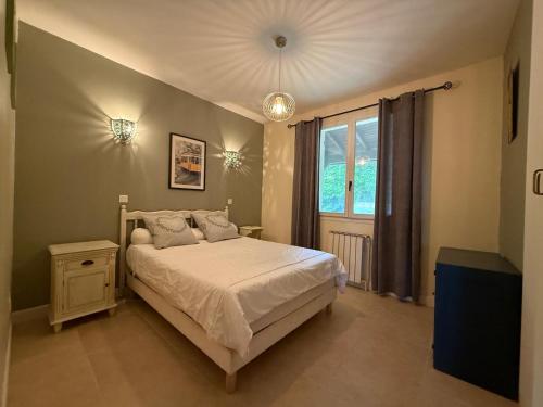 a bedroom with a white bed and a window at Les coquelicots in Villeneuve-sur-Lot