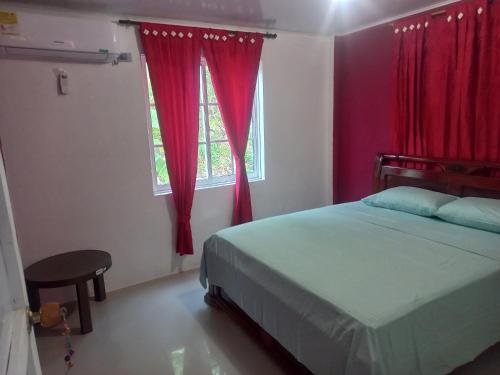 a bedroom with a bed and a window with red curtains at Posada paradise suite in Providencia