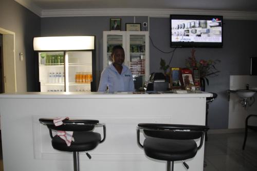 a woman standing behind a counter in a bar at Asante Apartments in Livingstone