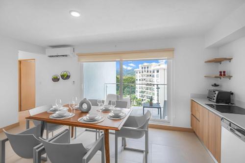 a kitchen and dining room with a table and chairs at Upstay - Brand New Condo w Pool - Near the Beach in Jacó
