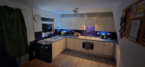 a kitchen with white cabinets and blue tiles on the wall at The Shinki House in Nottingham