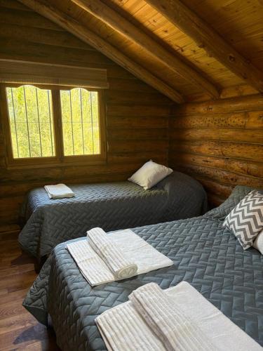 a room with two beds in a log cabin at Altandes Cabañas in Vista Flores