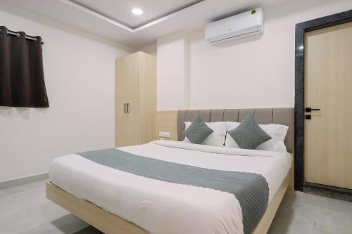 a bedroom with a large white bed with blue pillows at Hotel Saffron Groves in Hyderabad