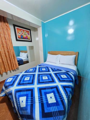 a bedroom with a blue and white bed with a mirror at Hostal Leo in Lima