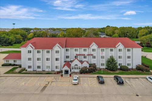 a large white building with a red roof at Ramada Limited by Wyndham, Bloomington I-55 & I-74 IL in Bloomington