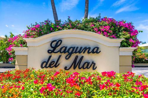 un panneau pour La Réunion del Mar avec des fleurs dans l'établissement Laguna Del Mar #19 - Seven Mile Beach, à Dog City
