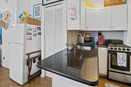 une cuisine avec des armoires blanches et un comptoir noir dans l'établissement Holiday stays now available! Easy beach access!, à New Smyrna Beach