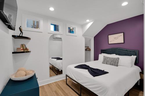 ein Schlafzimmer mit einem Bett mit einer lila Wand in der Unterkunft Elegant Stay Across From Fq W Free Parking in New Orleans