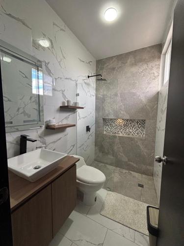 a bathroom with a toilet and a sink and a shower at Casa en Puyo Amazonía "Villa Coral" in Puyo