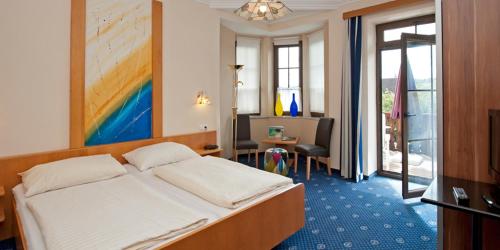 Una habitación de hotel con una cama y una sala de estar. en Hotel Kärntnerhof Velden, en Velden am Wörthersee