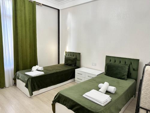 ガバラにあるQafqaz Qabalandia Deluxeの緑のカーテンがかかった部屋にベッドが2つ