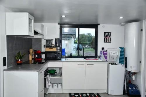 a kitchen with white cabinets and a sink and a window at Eden House in Saint-Pierre-Canivet