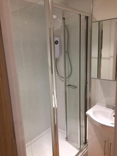 a shower with a glass door next to a sink at Modern 1 Bed City Centre Flat in Nottingham