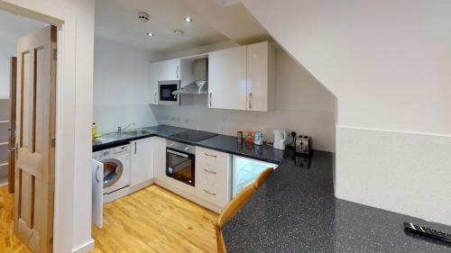 a kitchen with white cabinets and a washer and dryer at Modern 1 Bed City Centre Flat in Nottingham