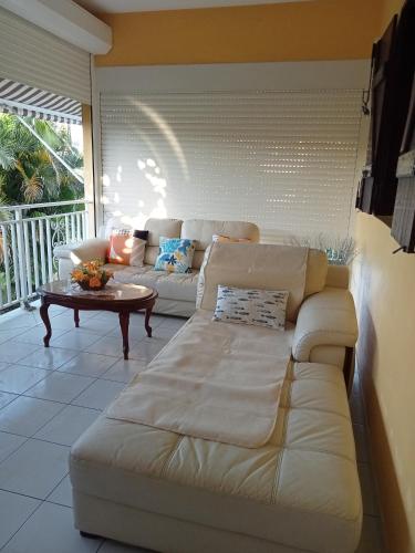 a living room with a white couch and a table at Villa Grandes pièces in Petit-Bourg