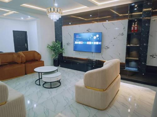 a living room with two chairs and a tv at Ike Service Apartments in Owerri