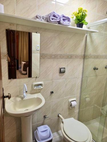 a bathroom with a sink and a toilet and a mirror at Hotel Paraiso Belém in Belém
