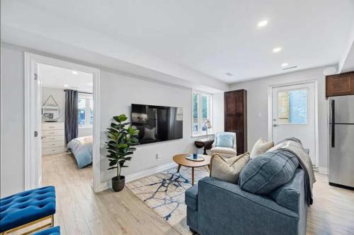 a living room with a blue couch and a tv at Casa Hotel Stylish Modern Family Suite with Patio in Toronto