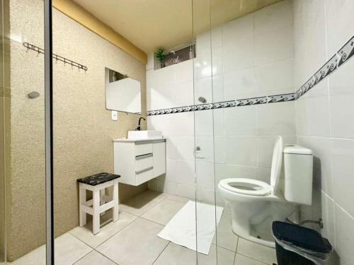 a bathroom with a toilet and a glass shower at Pousada da Cia in Blumenau