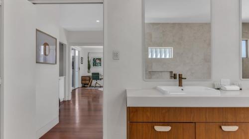 a white bathroom with a sink and a hallway at Solara in Kingscliff