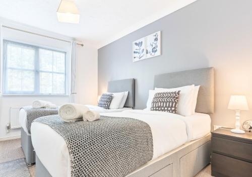 a white bedroom with two beds and a window at Central Peaceful Home with Parking, Wi-Fi and Garden in Stafford