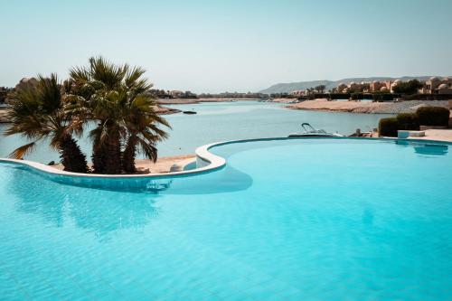 a large swimming pool with palm trees in the water at Nayah Stays, Cozy lagoons terrace one ensuite Apt in Hurghada