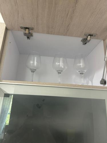 four wine glasses sitting on top of a shelf at Confortable Apartamento in Barranquilla